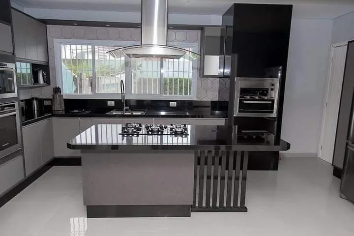 Cozinha com ilha em pedra preta e cooktop, obra da Mega