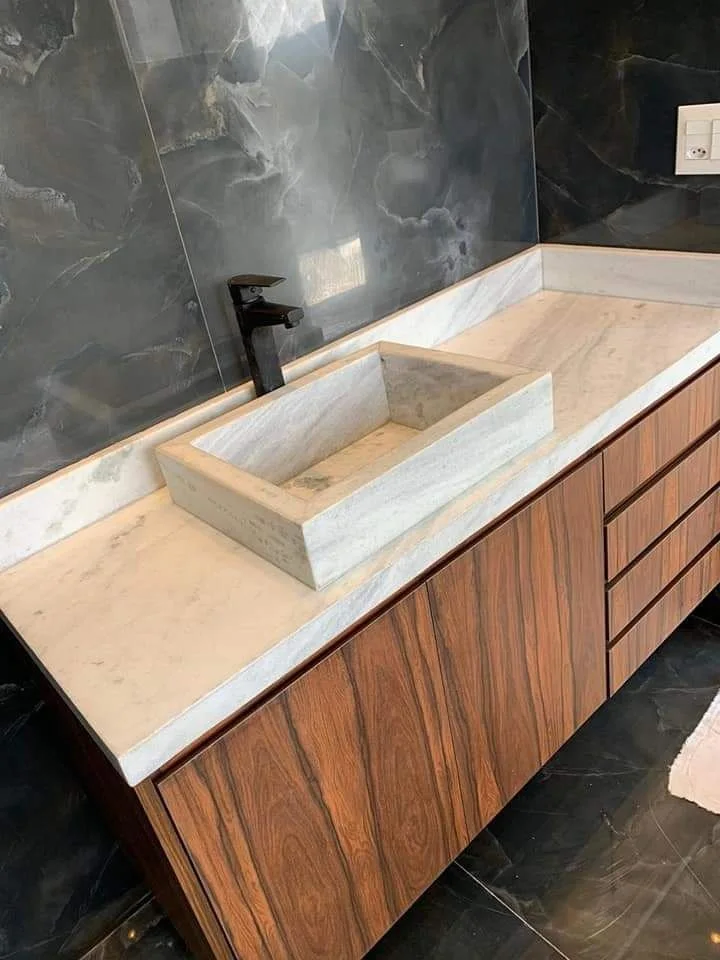 Banheiro com cuba esculpida em mármore claro, obra da Mega